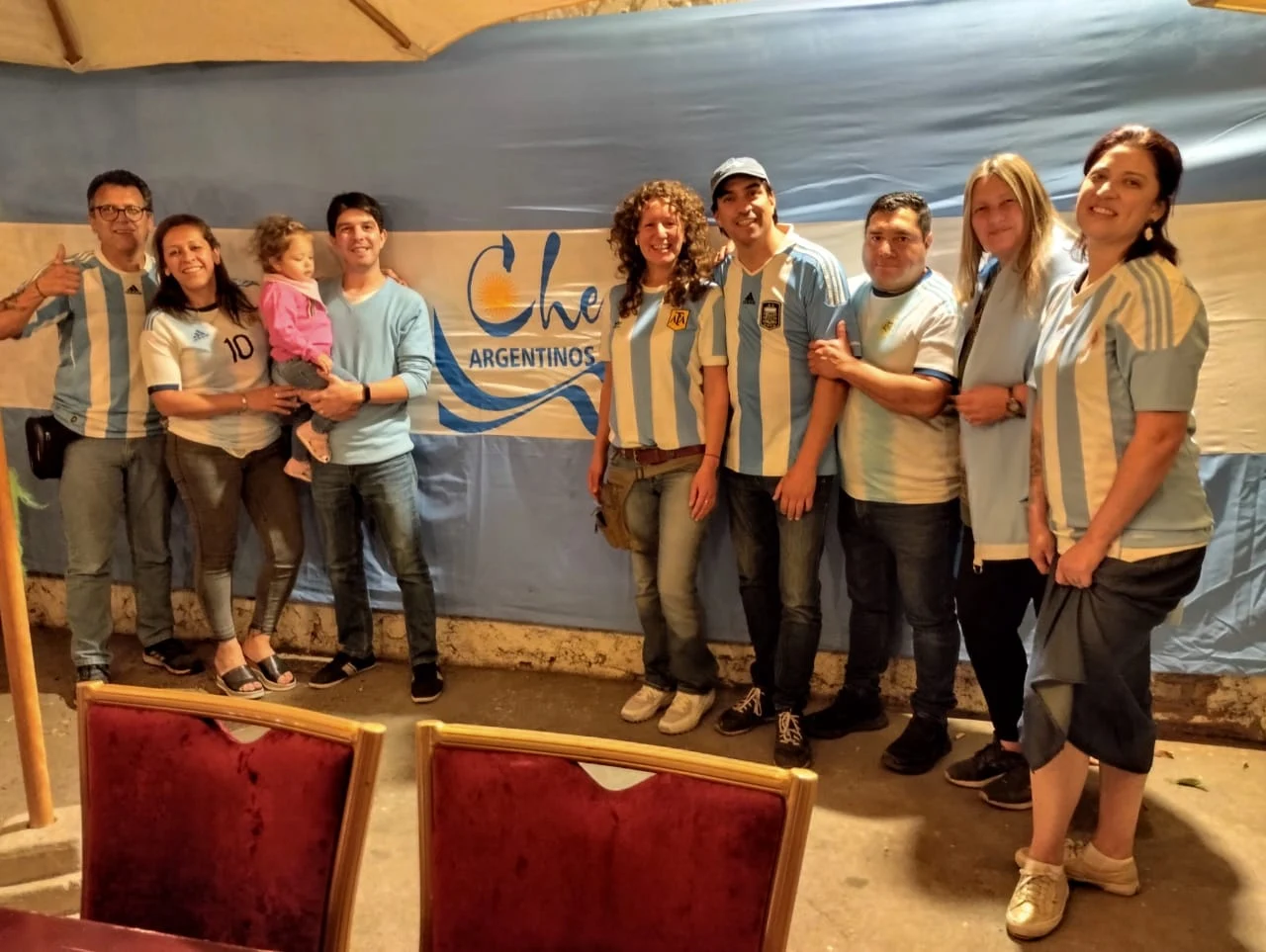 Integrantes de Che Argentinos reunidos en el Refugio junto a la bandera de la comunidad