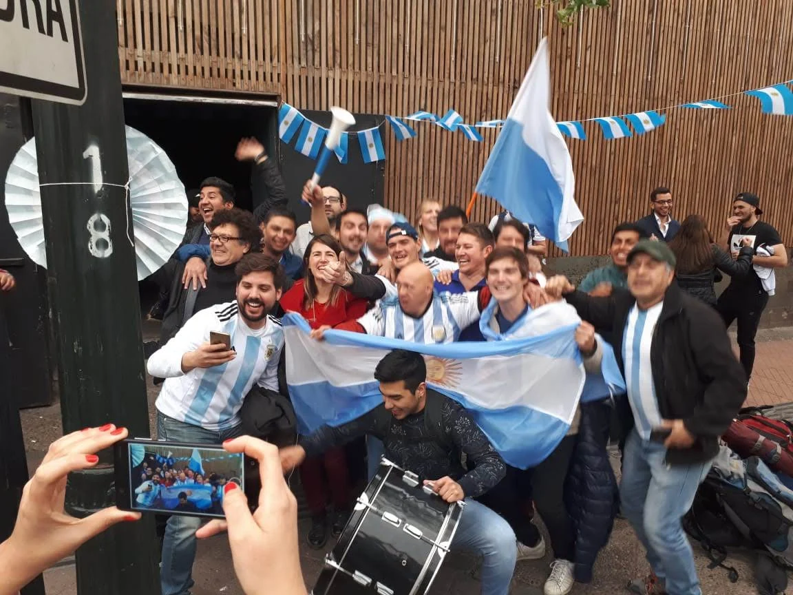 Hinchas de Che Argentinos alentando con banderas y camisetas argentinas